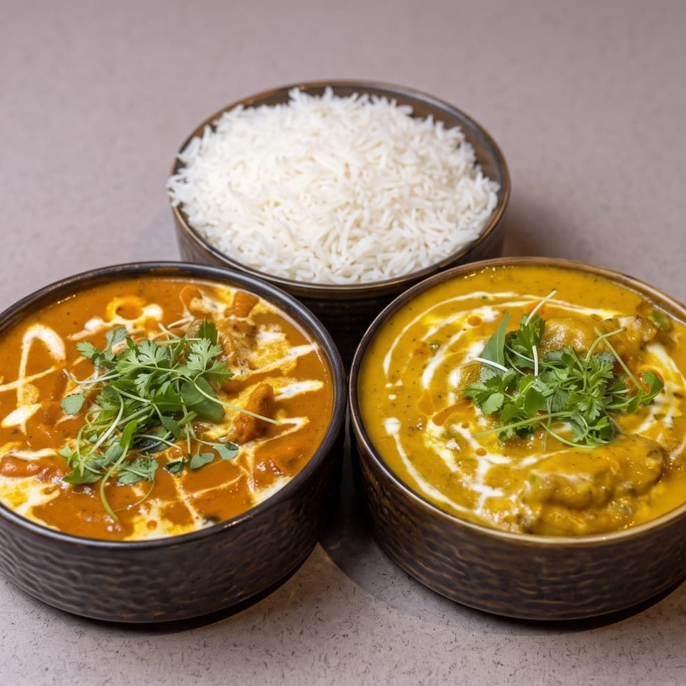 Two bowls of Indian curry, one orange and one yellow, with a bowl of white rice.